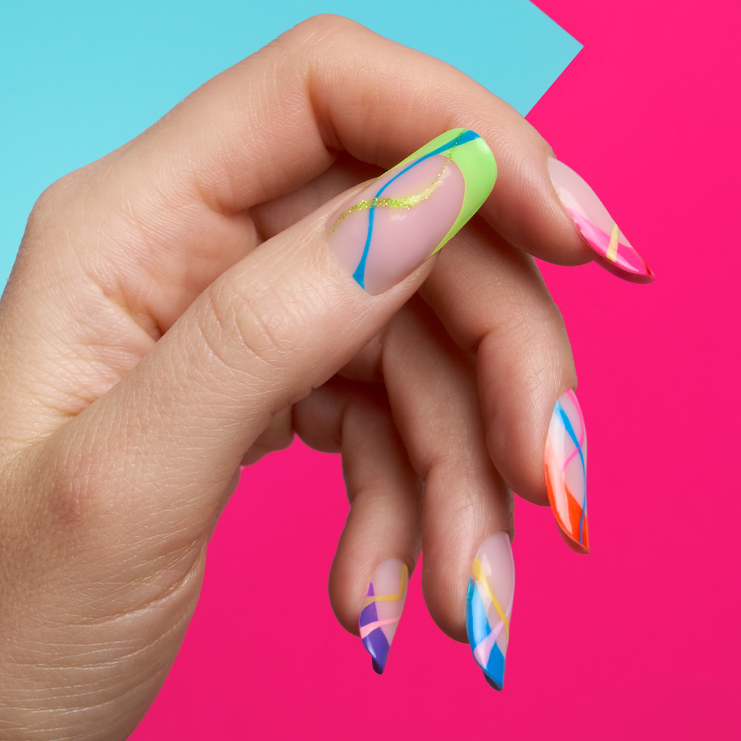 Mano con nail art geometrica su smalto semipermanente nude: linee neon verde, blu e glitter oro. Brand Passione Beauty