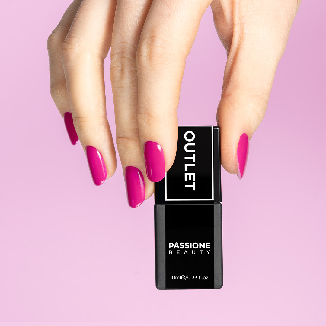 Smalto semipermanente fucsia acceso Passione Beauty su unghie a mandorla. Mano che tiene flacone nero linea Outlet. Nail art professionale.