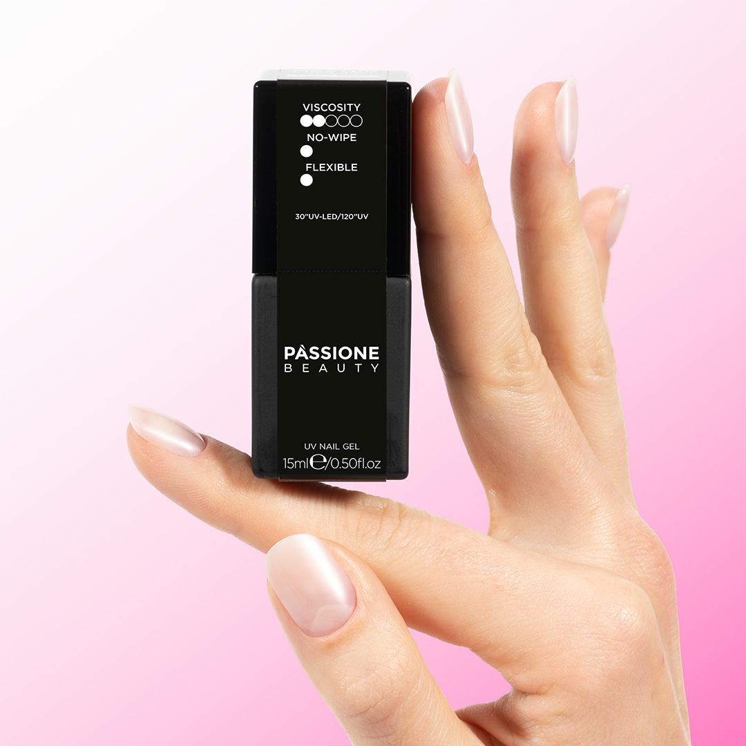 Passione Beauty Master Gloss top coat transparente brillante para uñas semipermanentes sostenido entre los dedos sobre fondo rosa