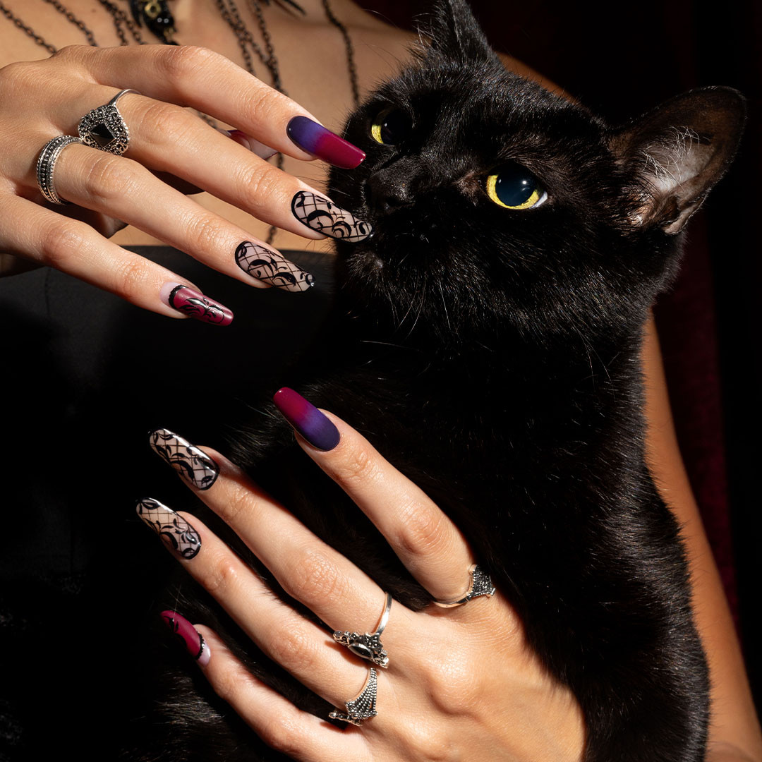 Passione Beauty nail art sur ongles longs avec vernis violet, noir et nude, motifs animaliers et détails pailletés